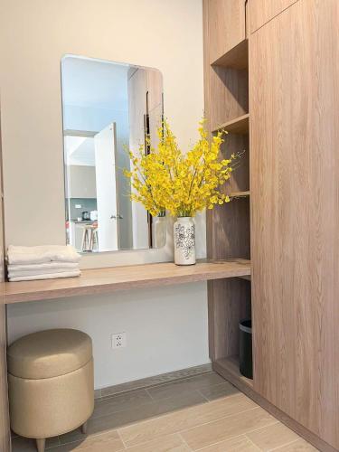 a vanity with a mirror and a vase with yellow flowers at The Sóng Vũng Tàu Escape Apartment in Vung Tau