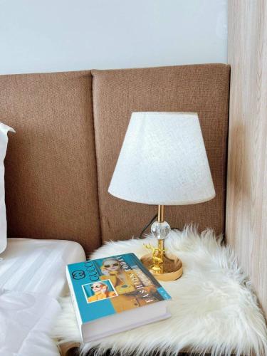 a bed with a book and a lamp on a table at The Sóng Vũng Tàu Escape Apartment in Vung Tau