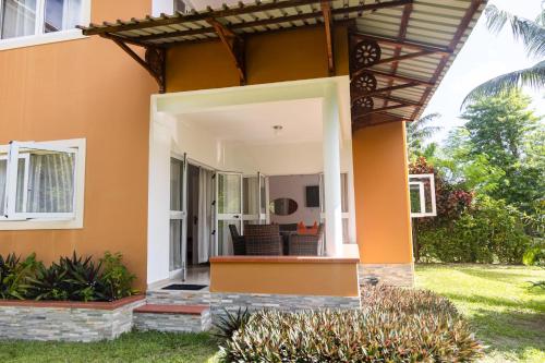 a home with an orange wall and a patio at Praslin Paradise in Baie Sainte Anne