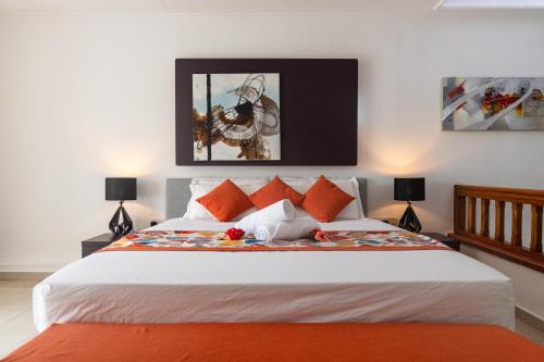 a bedroom with a large white bed with orange pillows at Praslin Paradise in Baie Sainte Anne