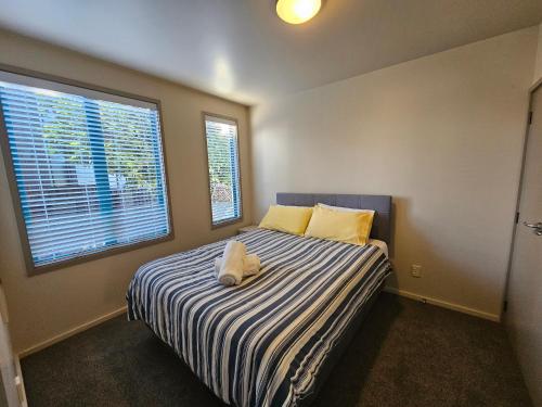- une chambre avec un lit rayé et 2 fenêtres dans l'établissement Parkhill Apartment in CBD, à Whangarei