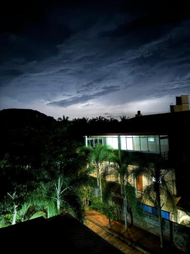 a building with palm trees in front of it at night at Gold Crown Residence in Dambulla