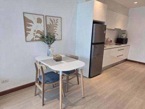 a kitchen with a white table and a refrigerator at The beach front Condo in Ban Saiyuan (1)
