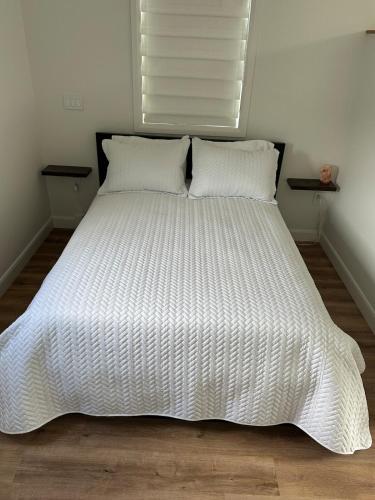 a bed with a white comforter and two pillows at Garden Suite with Pool and Sauna in Brampton