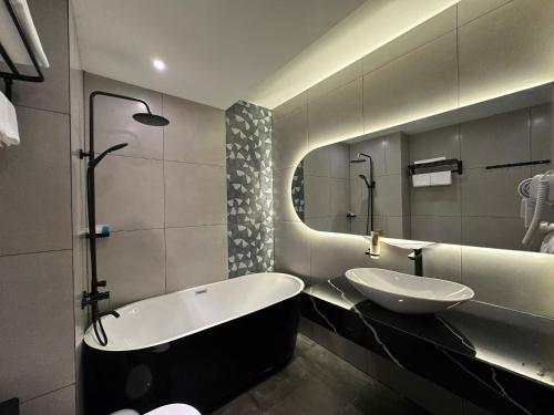 a bathroom with a tub and a sink and a mirror at LION 16 Hotel in Can Tho