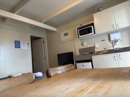 a room with a large wooden table and a kitchen at Camellia Court Family Motel in Taupo