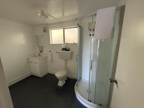 a bathroom with a toilet and a glass shower at Camellia Court Family Motel in Taupo