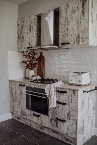 a kitchen with wooden cabinets and a stove top oven at Meadow View Cottage in Eccleston