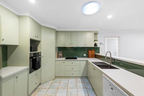a kitchen with white cabinets and a sink at Range Retreat - East Toowoomba in Toowoomba