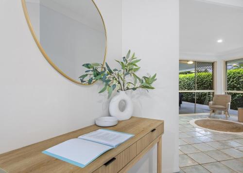 a mirror on top of a wooden table with a plant at Range Retreat - East Toowoomba in Toowoomba