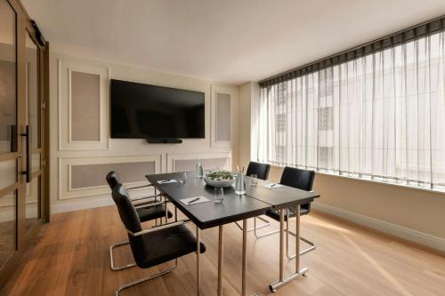 a dining room with a table and chairs and a television at JW Marriott Auckland in Auckland