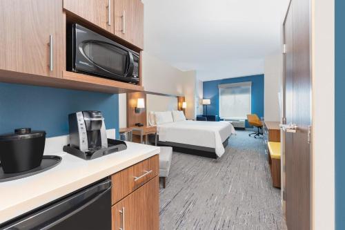 a small hotel room with a bed and a kitchen at Holiday Inn Express & Suites Houston S - Medical Ctr Area by IHG in Houston