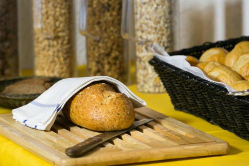 a loaf of bread on a cutting board with a knife at Hotel Adonis in Zermatt