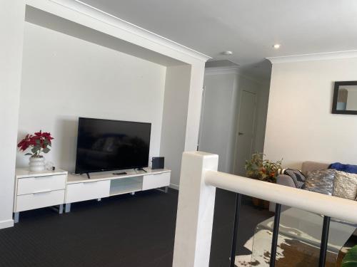 a living room with a flat screen tv and a couch at Bay side living in Redcliffe