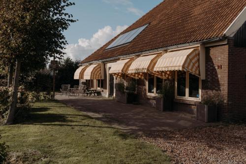 a building with a porch with a table and chairs at Camping De Tulpenweide lege Kampeerplaats, lege plaats op het gras zonder bed in Breezand