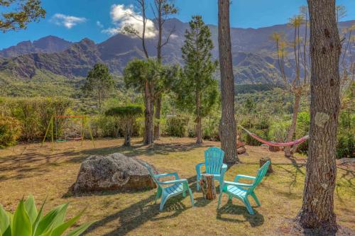 three chairs and a hammock in a park with mountains at La Villa Soalic in Cilaos