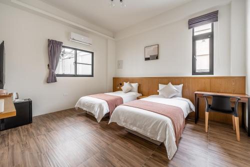 two beds in a room with a desk and a desk at Penghu Storyteller in Magong