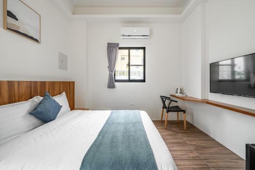 a bedroom with a bed and a tv and a desk at Penghu Storyteller in Magong