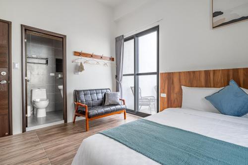 a bedroom with a bed and a chair and a bathroom at Penghu Storyteller in Magong