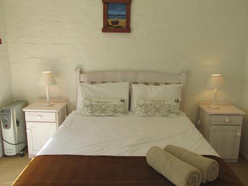 a bedroom with a white bed with two nightstands and two lamps at Point Village Accommodation - Hennie Bottom in Mossel Bay