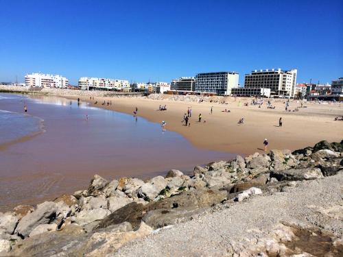 a group of people on a beach near the water at Tubarinho Apartment in Costa da Caparica