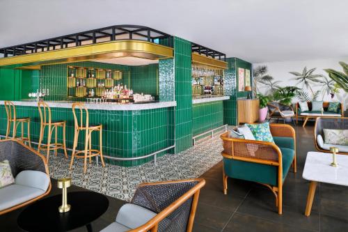 a restaurant with a green bar with chairs and tables at voco Dubai by IHG in Dubai
