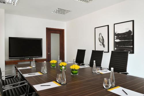 a conference room with a long table with chairs and a television at voco Dubai by IHG in Dubai
