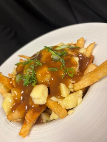 a plate of food with french fries and gravy at Holiday Inn Montreal Longueuil by IHG in Longueuil