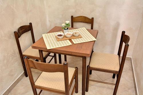 a wooden table with four chairs and a table with flowers on it at Step to Kotor bay St-oliv in Kotor