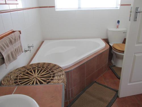 a bath tub in a bathroom with a toilet at Point Village Accommodation - Laurie's House in Mossel Bay