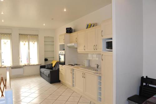 une cuisine avec des armoires blanches et un canapé dans une pièce dans l'établissement Appartement Trouville proche plage, à Trouville-sur-Mer