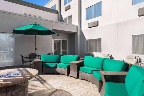 a patio with green chairs and an umbrella at Wingate by Wyndham Fletcher at Asheville Airport in Fletcher