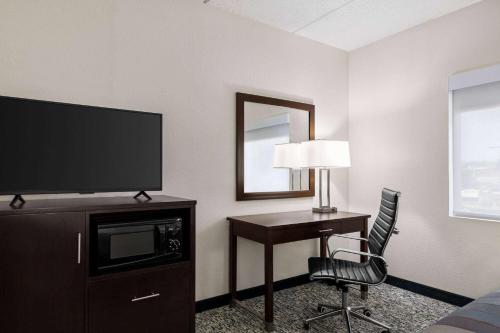 a hotel room with a desk with a television and a chair at Wingate by Wyndham Fletcher at Asheville Airport in Fletcher