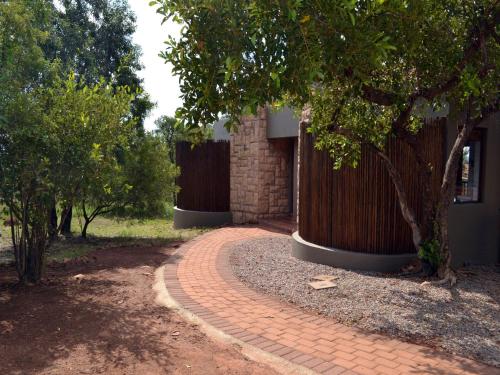 a brick walkway next to a building with trees at Elements Private Golf Reserve in Bela-Bela