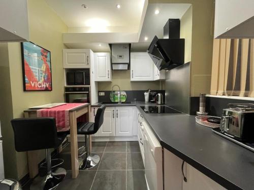 une cuisine avec des armoires blanches et une table à l'intérieur dans l'établissement AME Mombrun, à Vichy