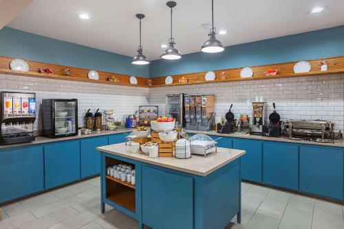 a kitchen with blue cabinets and a counter with food at Country Inn & Suites by Radisson, Lewisville, TX in Lewisville