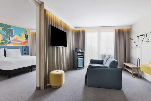 pokój hotelowy z łóżkiem, kanapą i telewizorem w obiekcie Spark by Hilton Vienna Messe Prater w Wiedniu