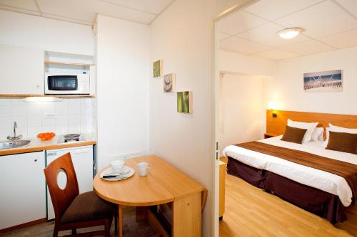 Cette chambre comprend un lit, une table et une cuisine. dans l'établissement Séjours & Affaires Rennes de Bretagne, à Rennes