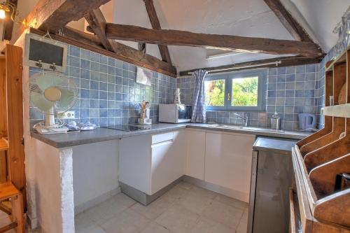 une cuisine avec des placards blancs et du carrelage bleu dans l'établissement Charme Rustique, Colombier, Cottage et Piscine, à Saint-Laurent-des-Hommes