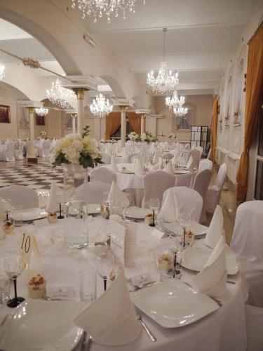 una sala per banchetti con tavoli e sedie bianchi e lampadari di Hotel Komfort Inn - Dwór Hubertus a Piekary Śląskie