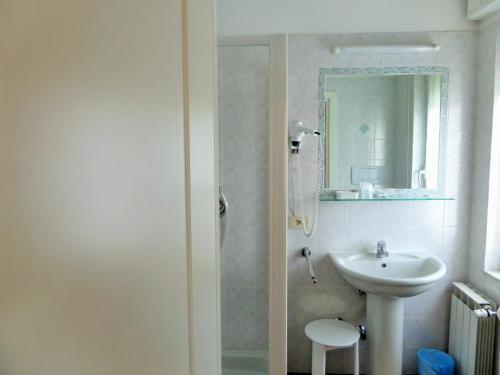 a white bathroom with a sink and a mirror at Hotel Lucerna in Arma di Taggia
