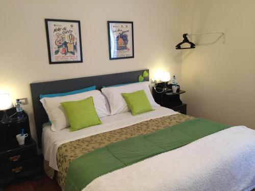 a bedroom with a bed with green and white pillows at Appartamenti I Giardini Di Villa Melzi in Bellagio