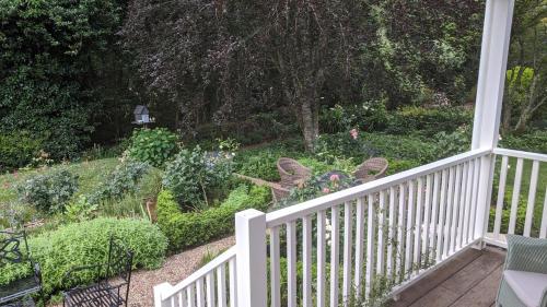 a porch with a white fence and a garden at Cherrywood-luxe retreat in the Southern Highlands in Exeter