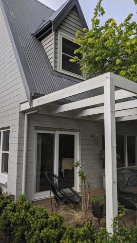 a white pergola on a house with two chairs at Cherrywood-luxe retreat in the Southern Highlands in Exeter