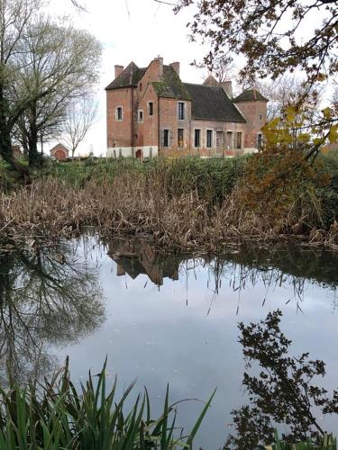 une vieille maison assise sur une colline à côté d'une nappe d'eau dans l'établissement Vieux château Saint-Claude, à Clux