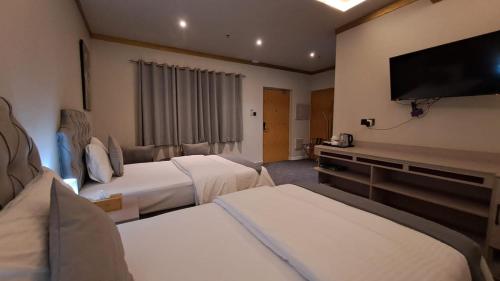 a hotel room with two beds and a flat screen tv at Daraysh Hotel in Sharjah