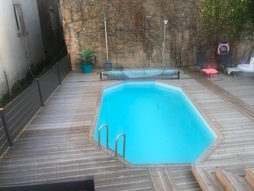 une grande piscine bleue sur une terrasse en bois dans l'établissement Charmante maison au cœur des vignes, à Paris-lʼHôpital