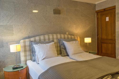 een slaapkamer met een bed met kussens en 2 lampen bij Hotel Wilgenhof in Maaseik