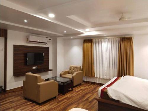 a hotel room with a bed and a tv at Hotel Vaishnavi Grand in Warangal