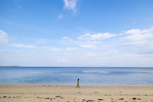 a person standing on a beach looking at the ocean at THE HERO VILLA 米原ビーチリゾートishigaki in Ishigaki Island